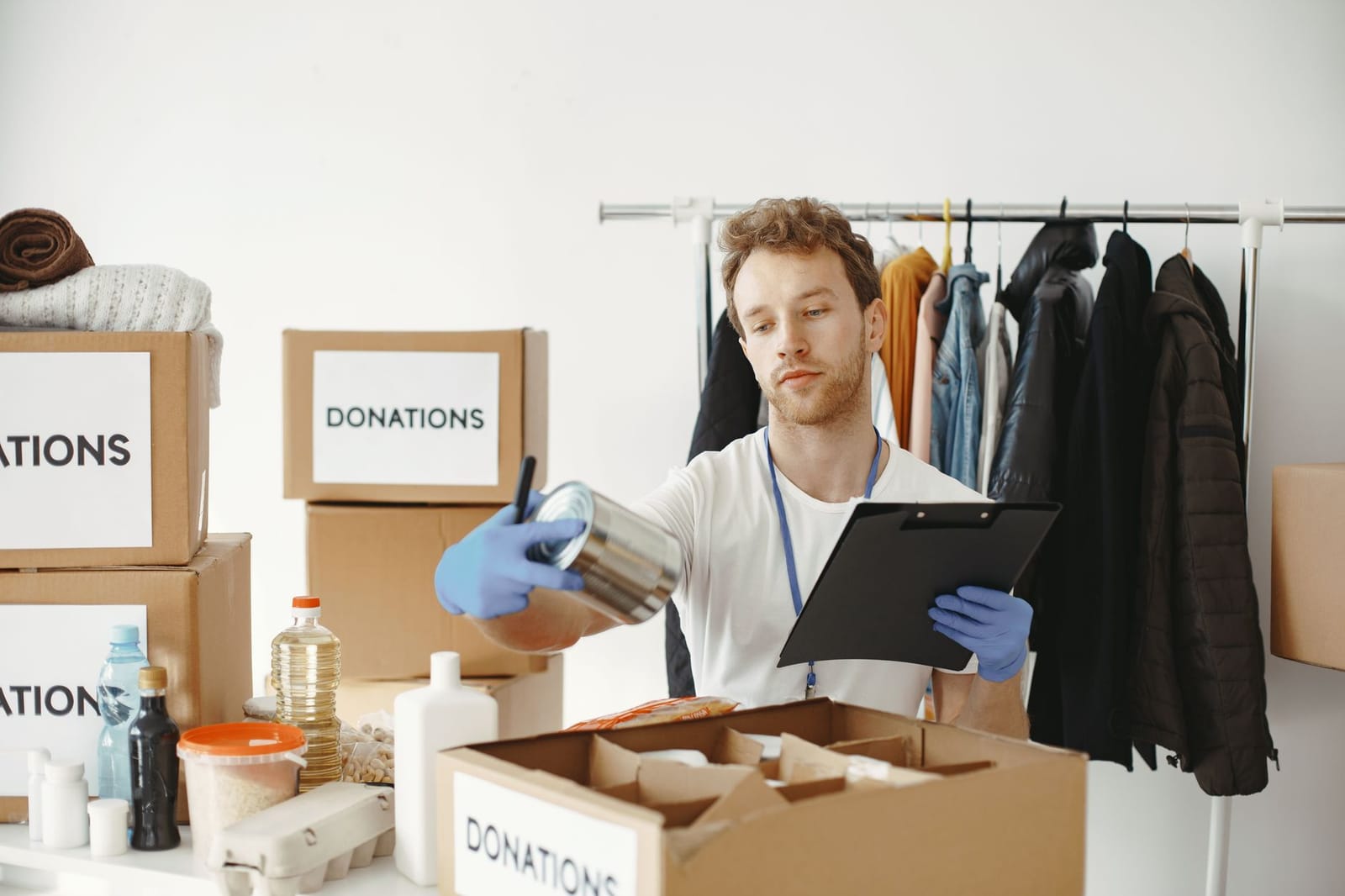 A volunteer in a community centre checking donated boxes against a clipboard.