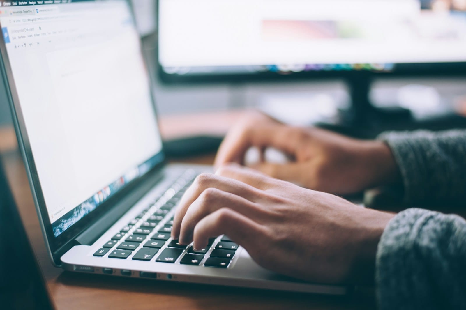 A journalist typing on a laptop at a desk.