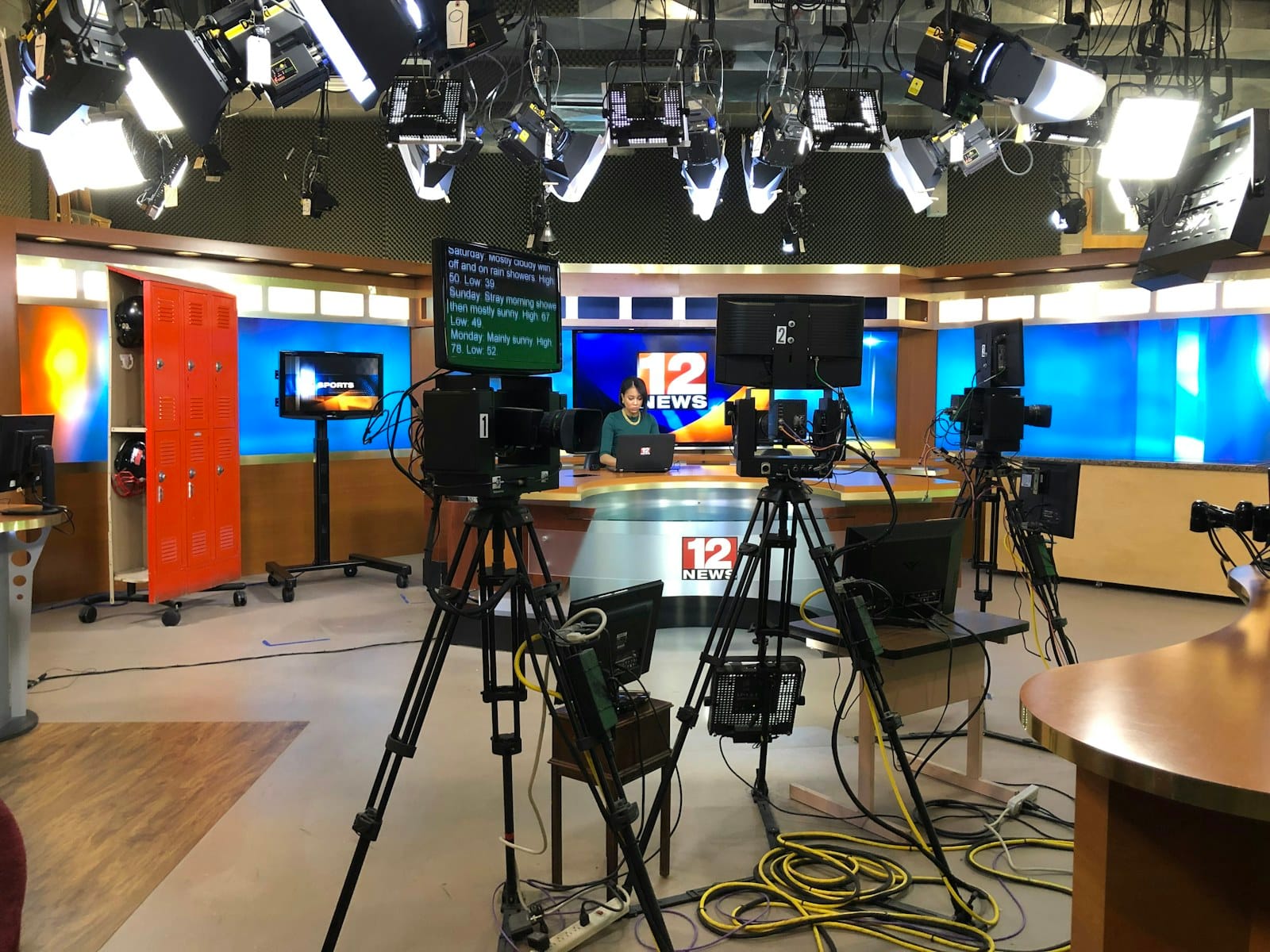 A working television news studio with cameras and monitors.