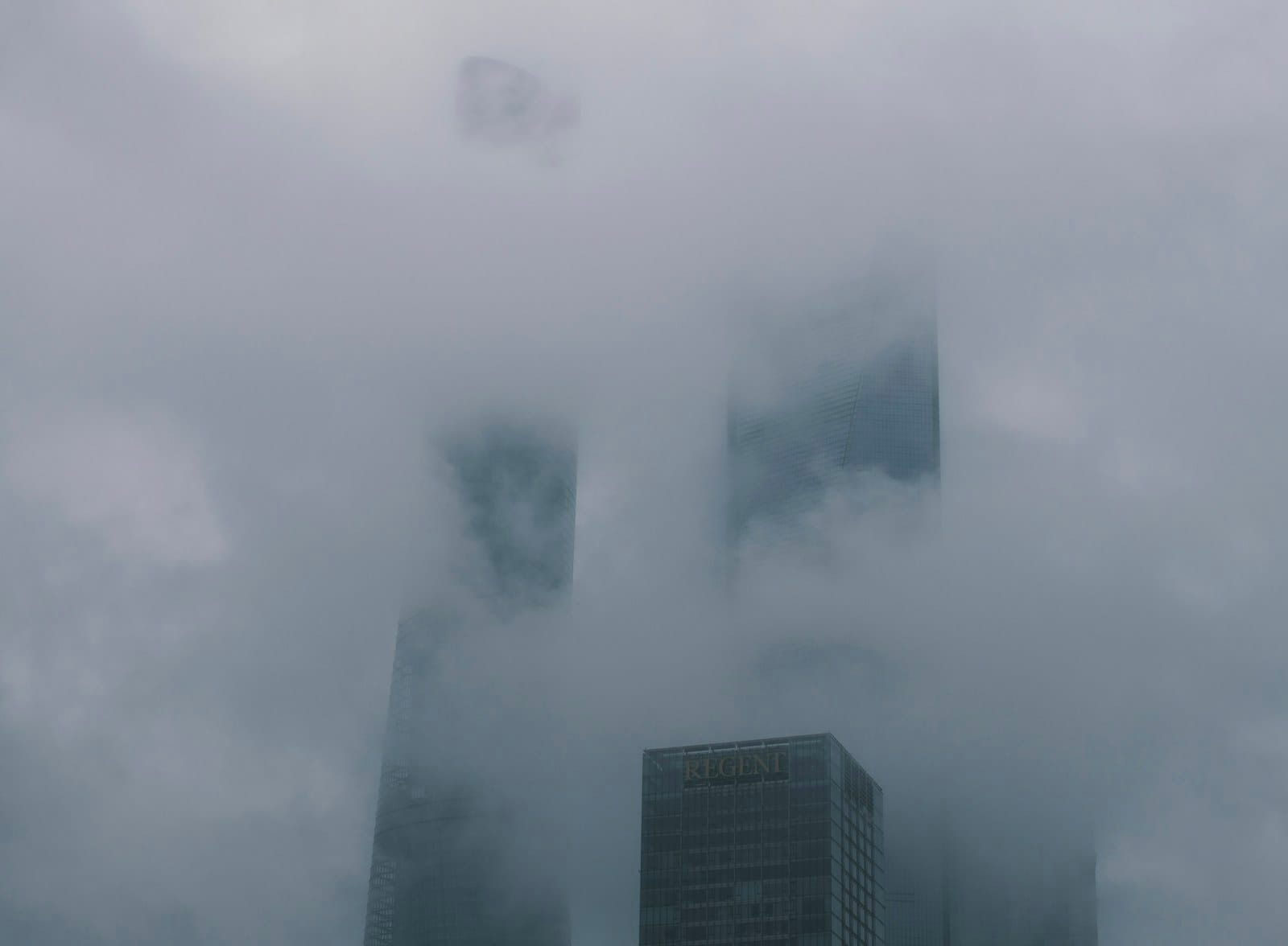 Skyscrapers rising through a thick blanket of low cloud.