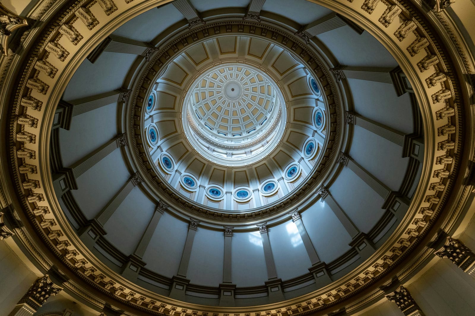 Looking straight up into the painted dome of a state capitol rotunda.