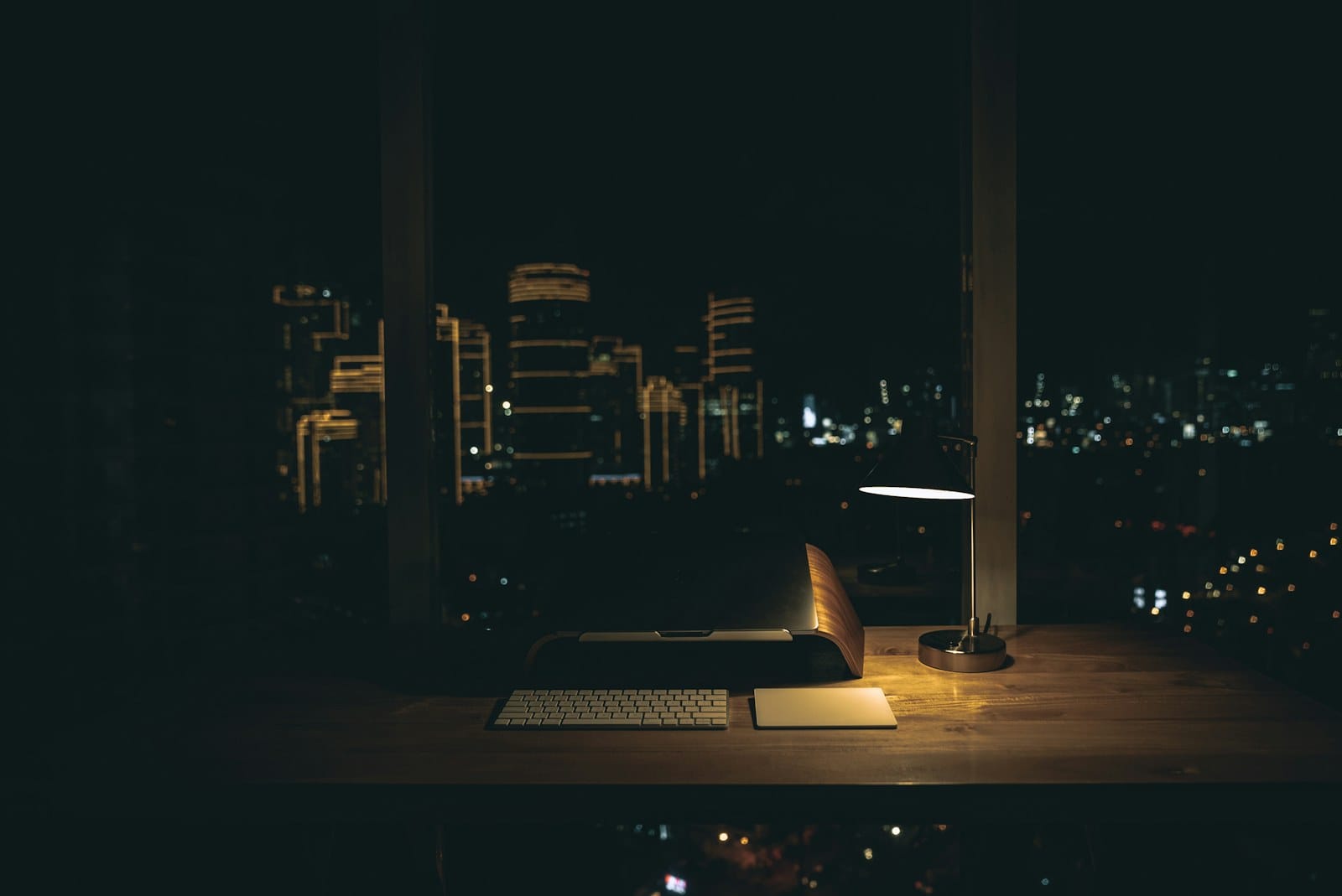A desk lamp lit over a work desk at night.