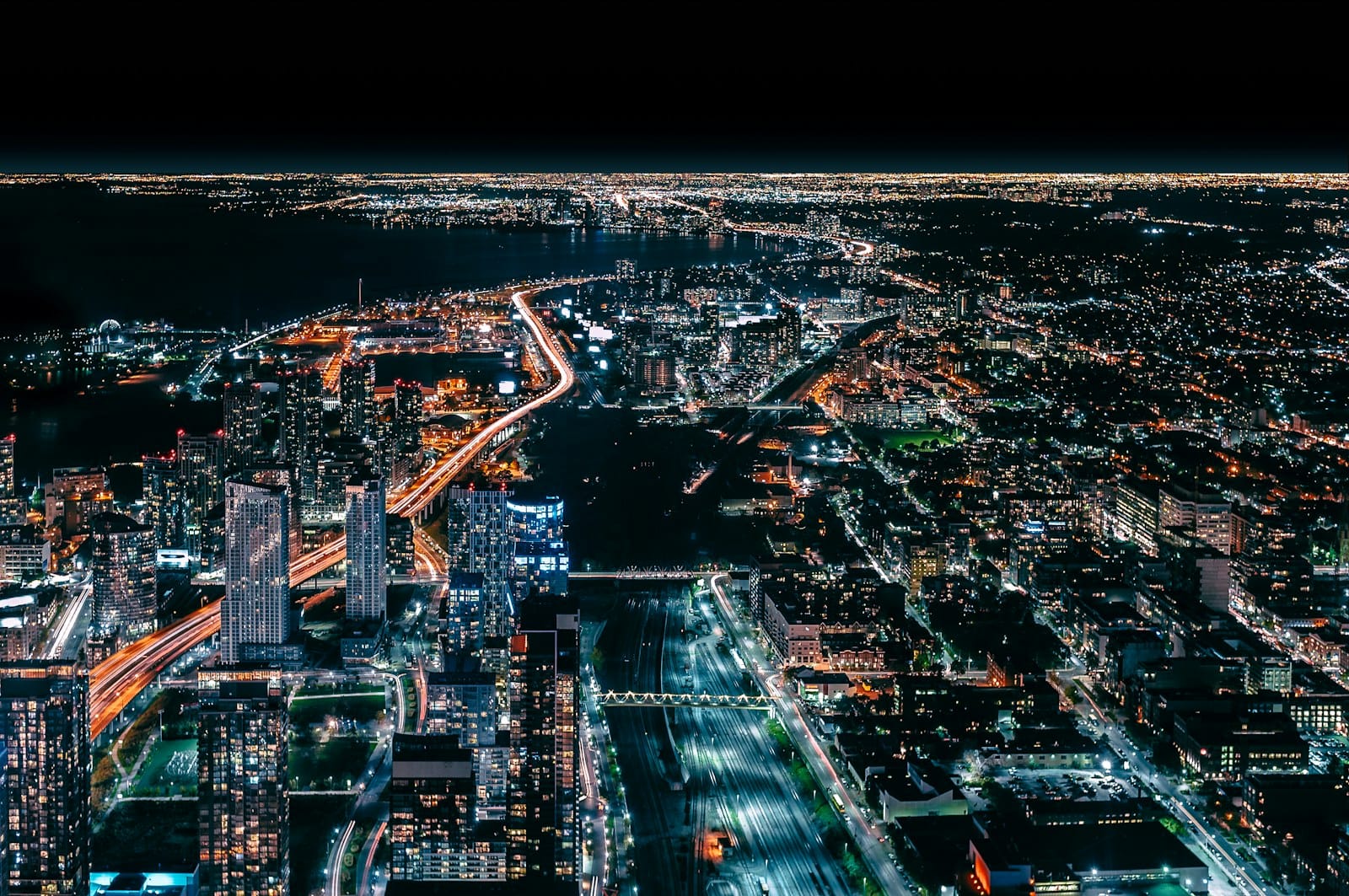 A city grid seen from above at night, streets lit in a fine mesh of light.
