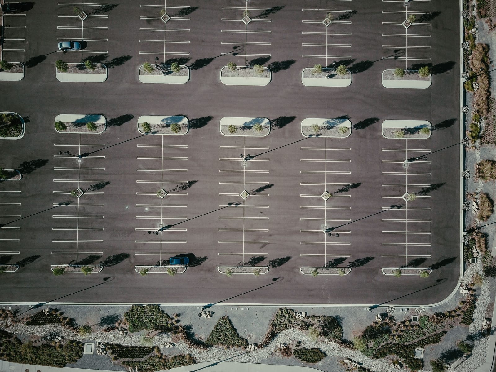 An empty parking lot from above, its bays ruled into a neat grid.