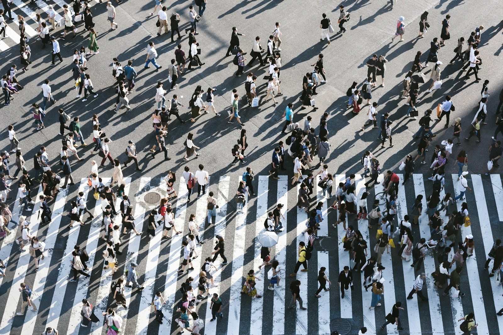 A city intersection seen from directly above, with pedestrians crossing in every direction.
