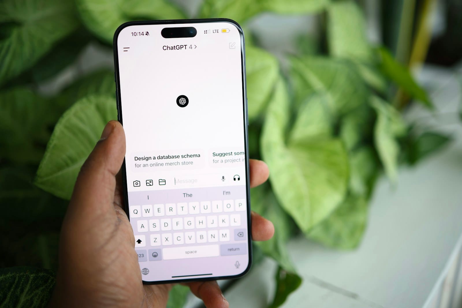 A hand holding a phone with ChatGPT open.