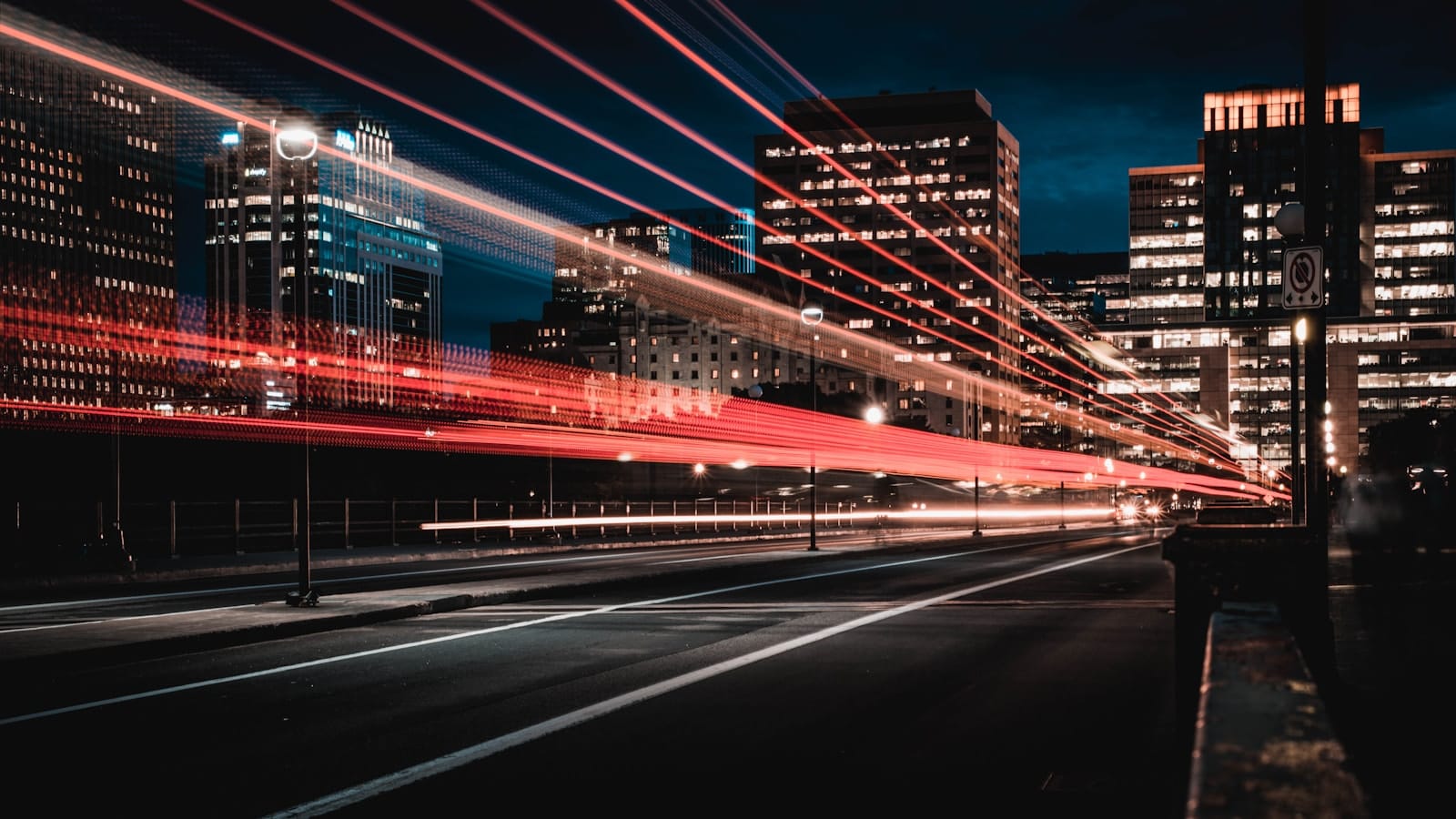 Light trails streaking down a city road at dusk.