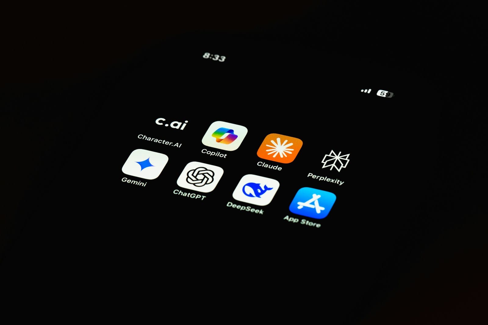 A close-up of a phone showing AI assistant app icons.