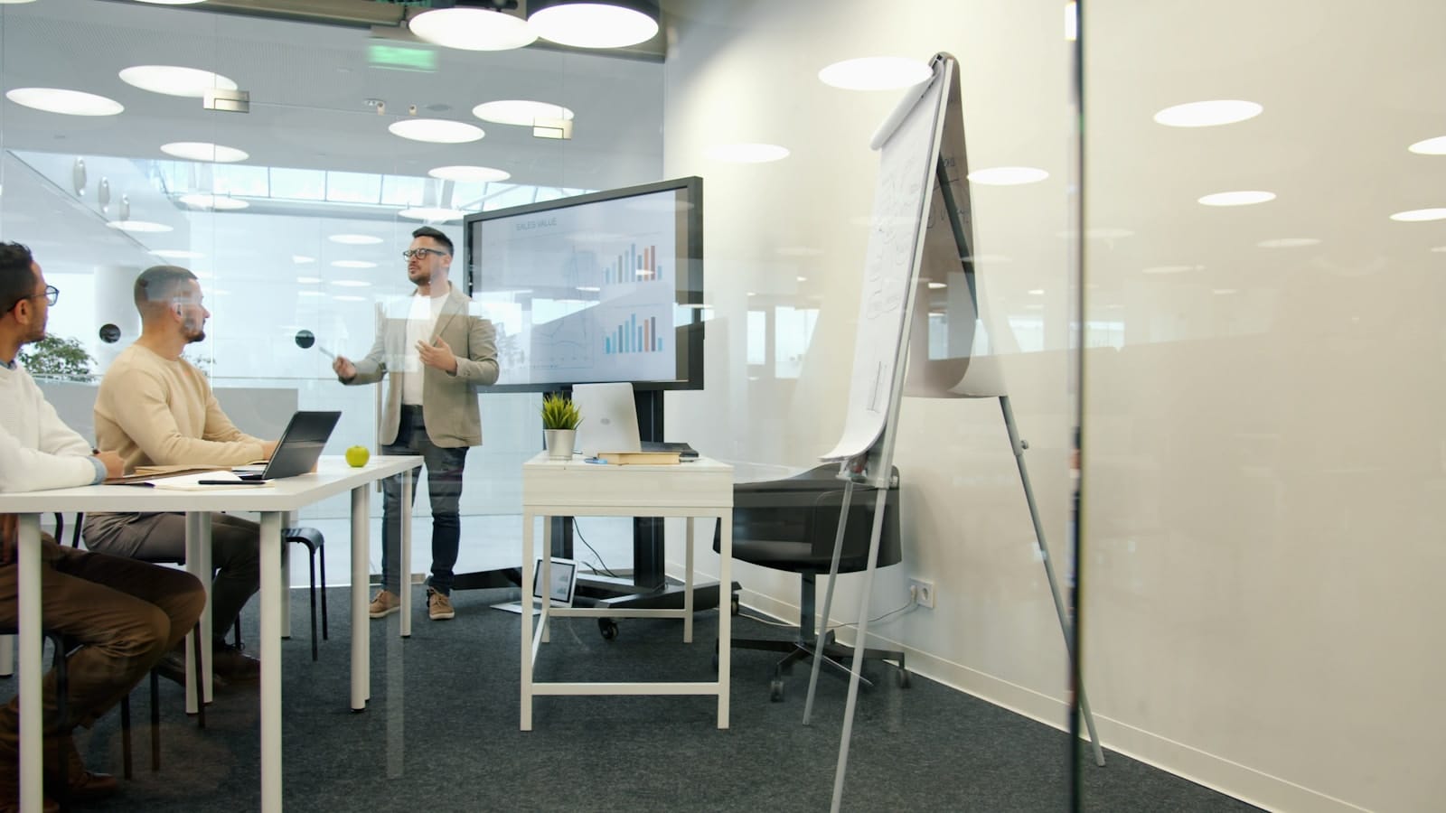 A strategist presenting to colleagues in a glass meeting room.