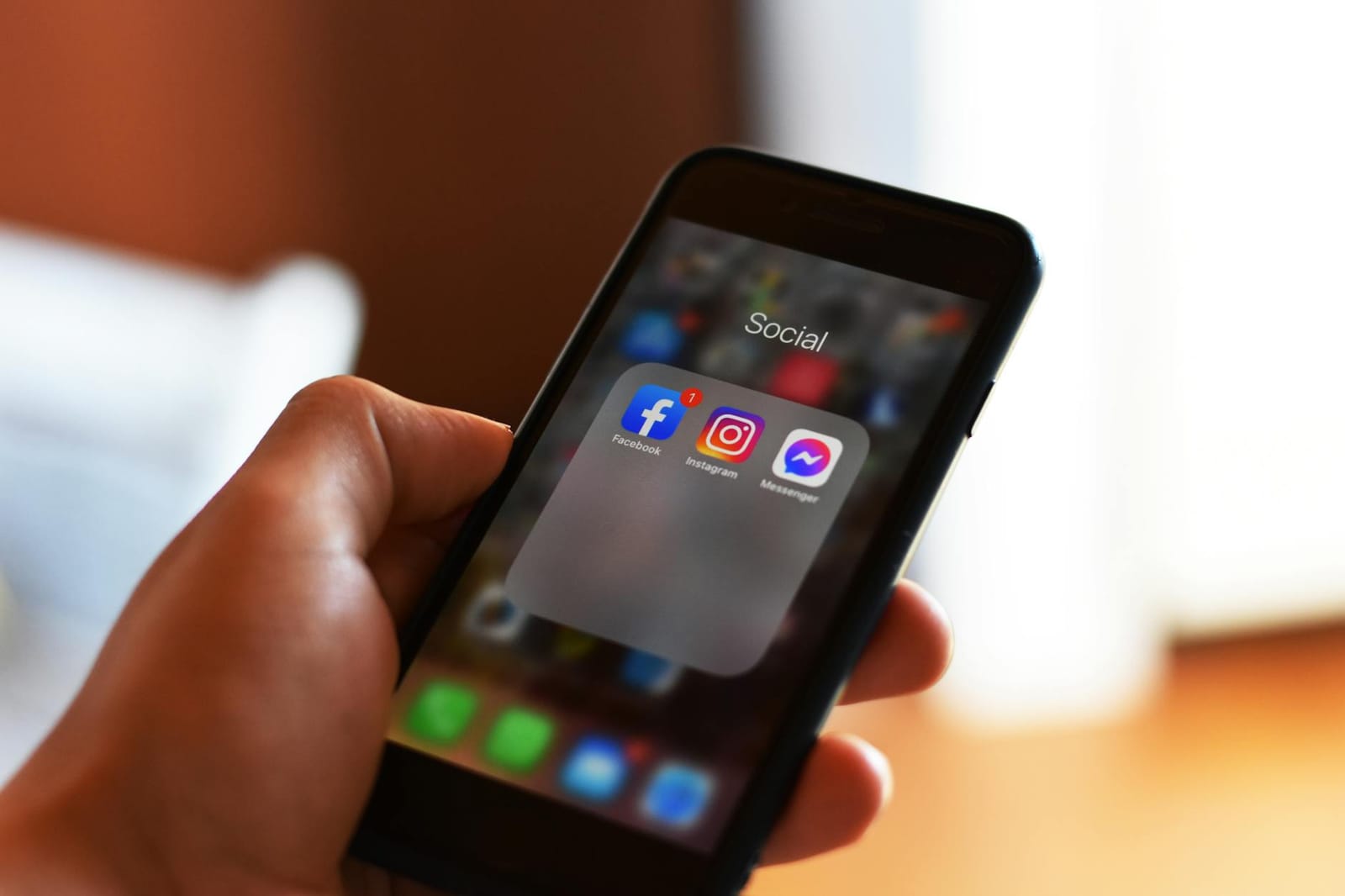 A hand holding a phone open on social media apps.