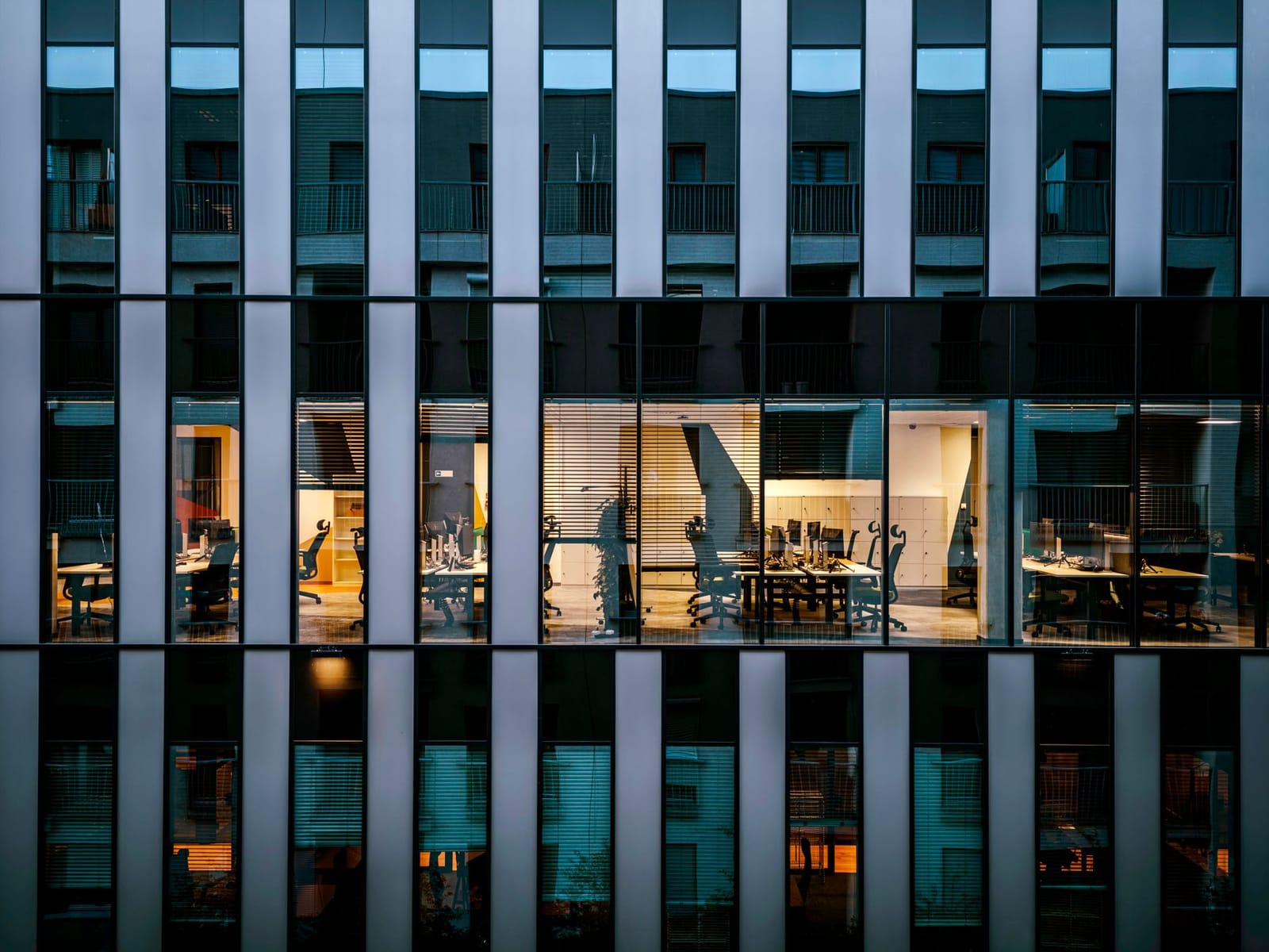 A modern glass office building at dusk.