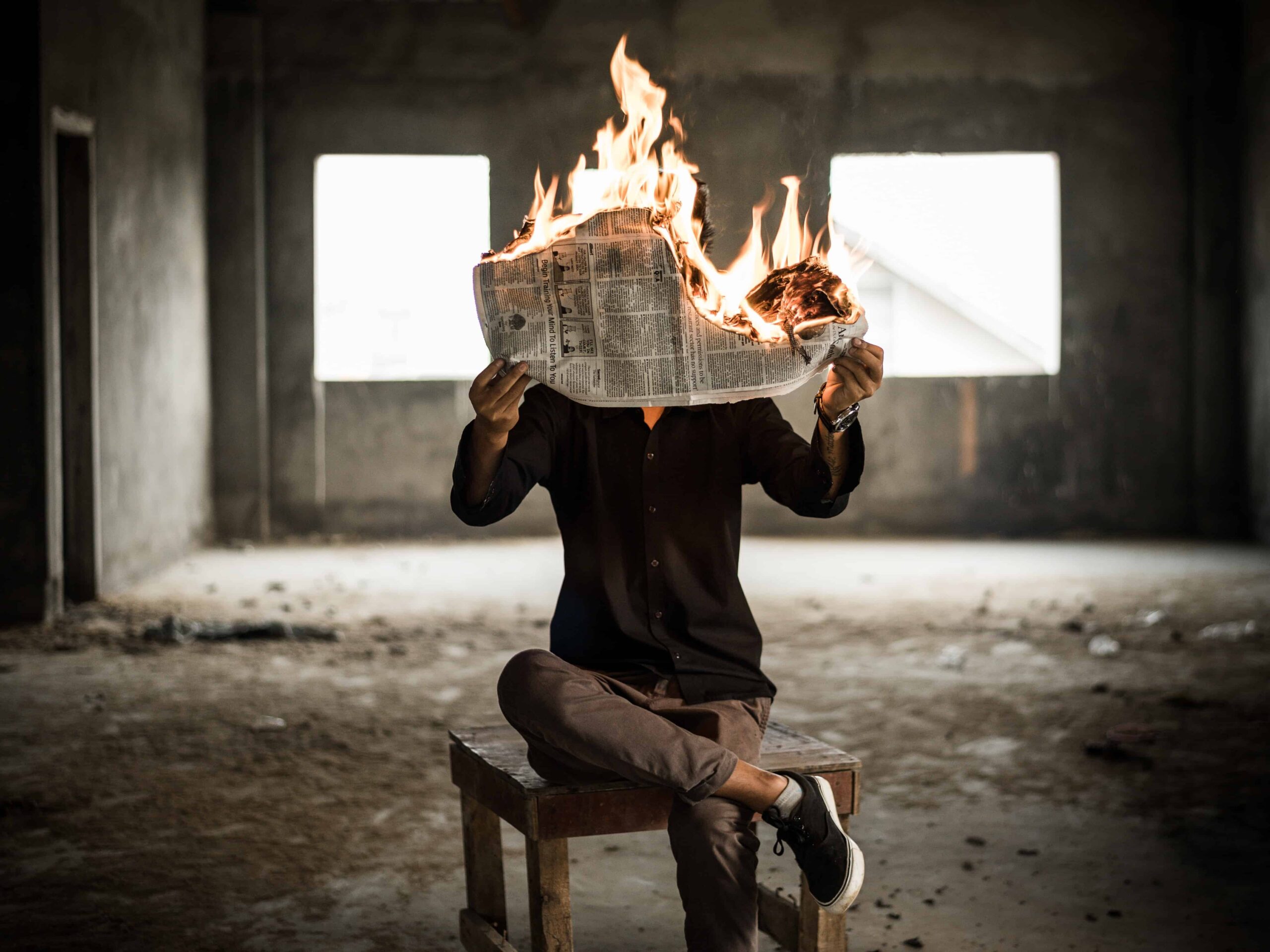 man holding burning newspaper in his hands